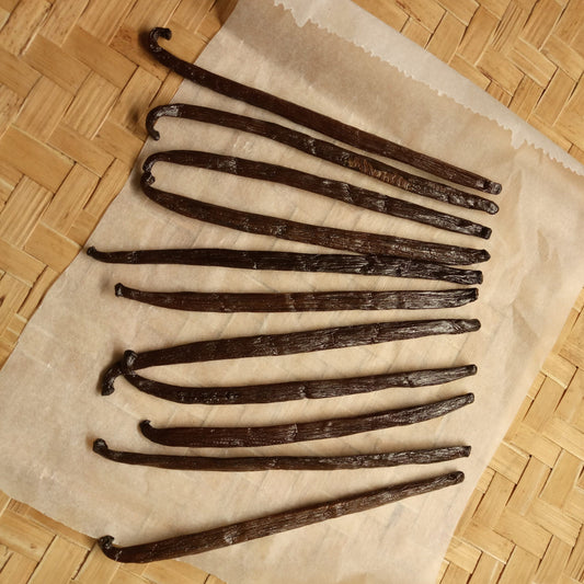Vanilla beans on a piece of parchment paper on a woven surface