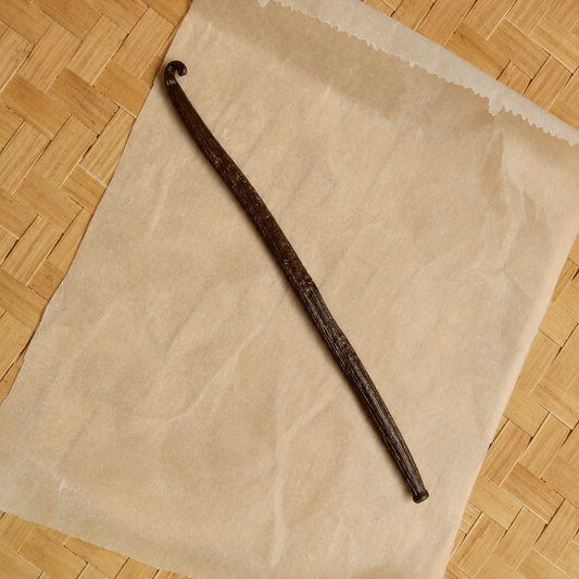 Vanilla stick on a piece of brown paper with a woven wooden surface background